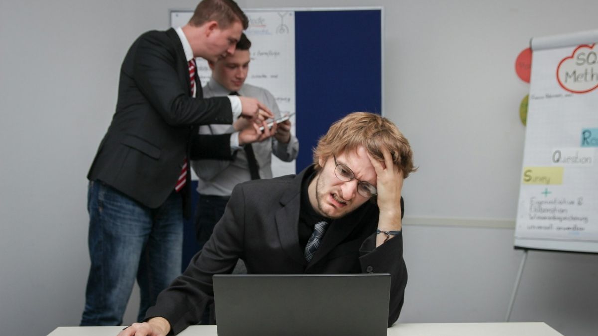 Nezadovoljan klijent, problem, rizici, greške, loše raspoložen poslovni čovjek gleda u laptop, iza njega dvojica traže rješenje