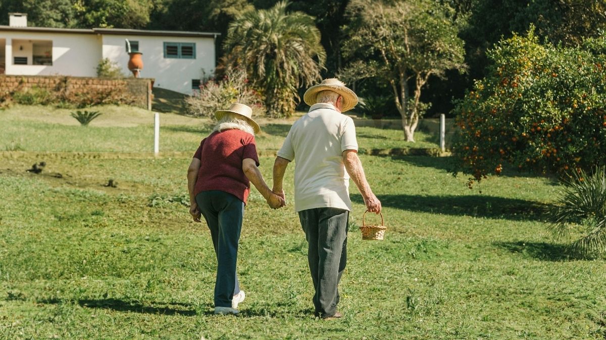 Umirovljenici, niska mirovina, gospođa i gospodin šeću vrtom, drže se za ruke